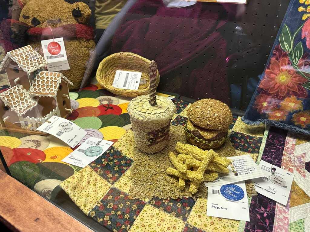 three-dimensional model of a burger, fries, and milkshake made entirely of seeds.