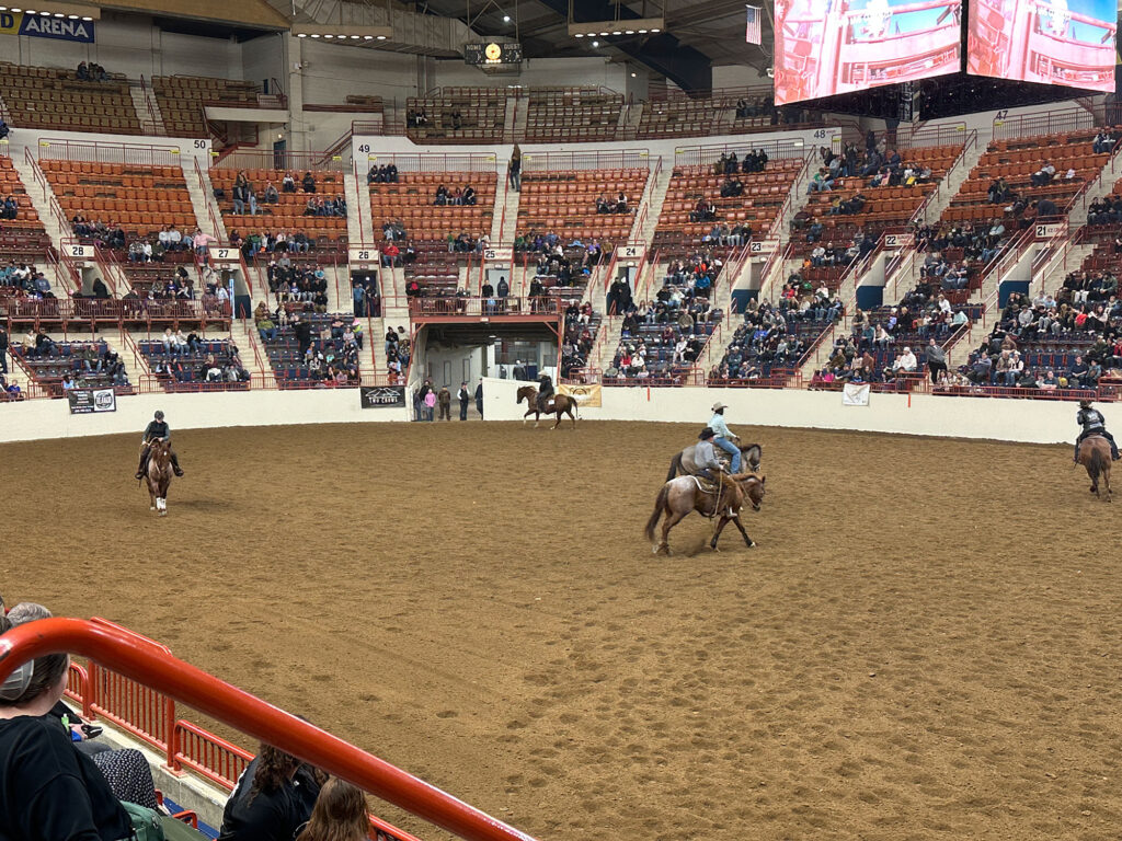 several people riding horses in a large arena with a dirt floor