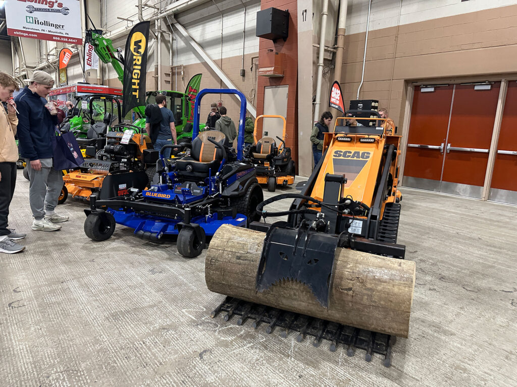 a row of small tractors in yellow and blue on display in an indoor expo space.
