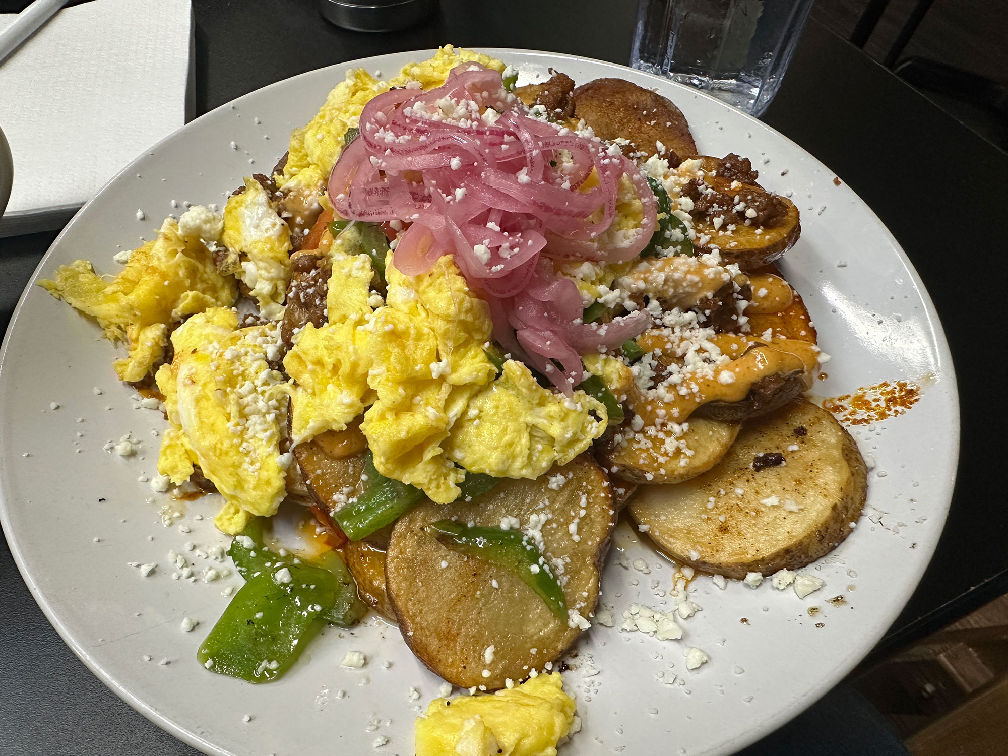 plate with a breakfast skillet of sliced potatoes, scrambled egg, pickled red onion and chorizo