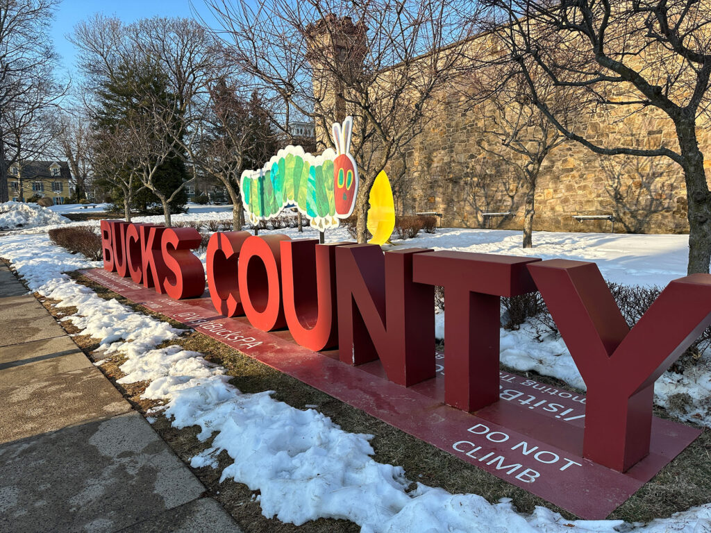 Large red scuplture of the words "Bucks County" with a cutout of the Very Hungry Caterpillar on top