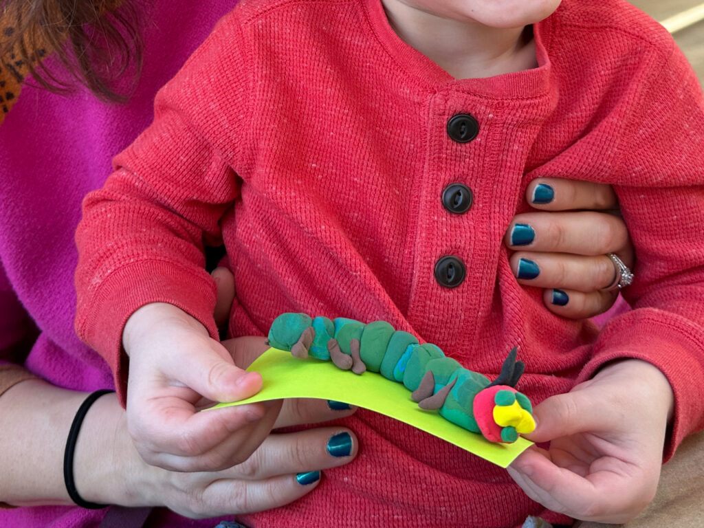 close-up of a child's clay model of a caterpillar with green body and red head