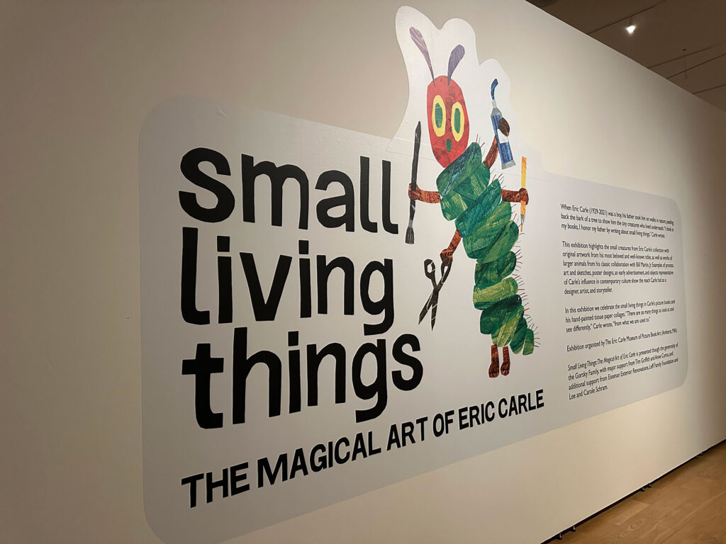 white wall with a large panel that reads "Small Living Things: The magical art of Eric Carle" with an image of the Very Hungry Caterpillar