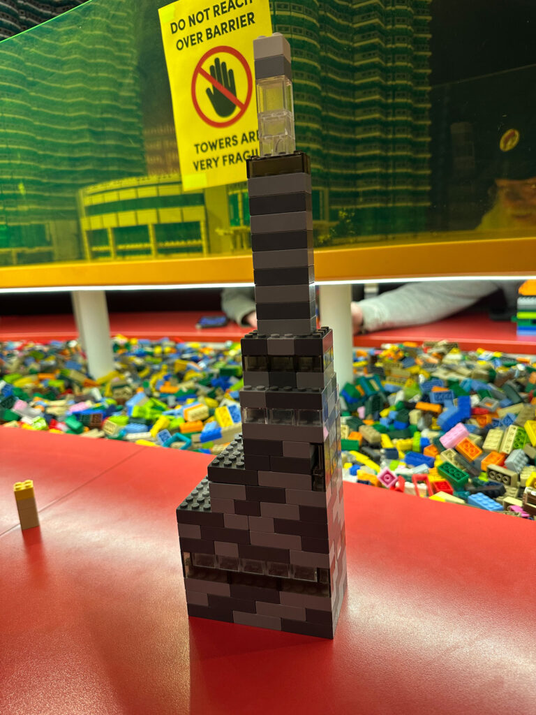 LEGO tower built of light and dark gray bricks tapering to a spire on top