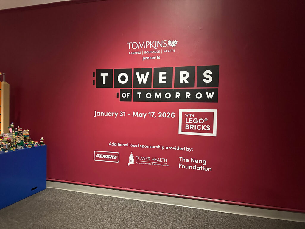 Red wall with the words "Towers of Tomorrow" in white letters with black blocks