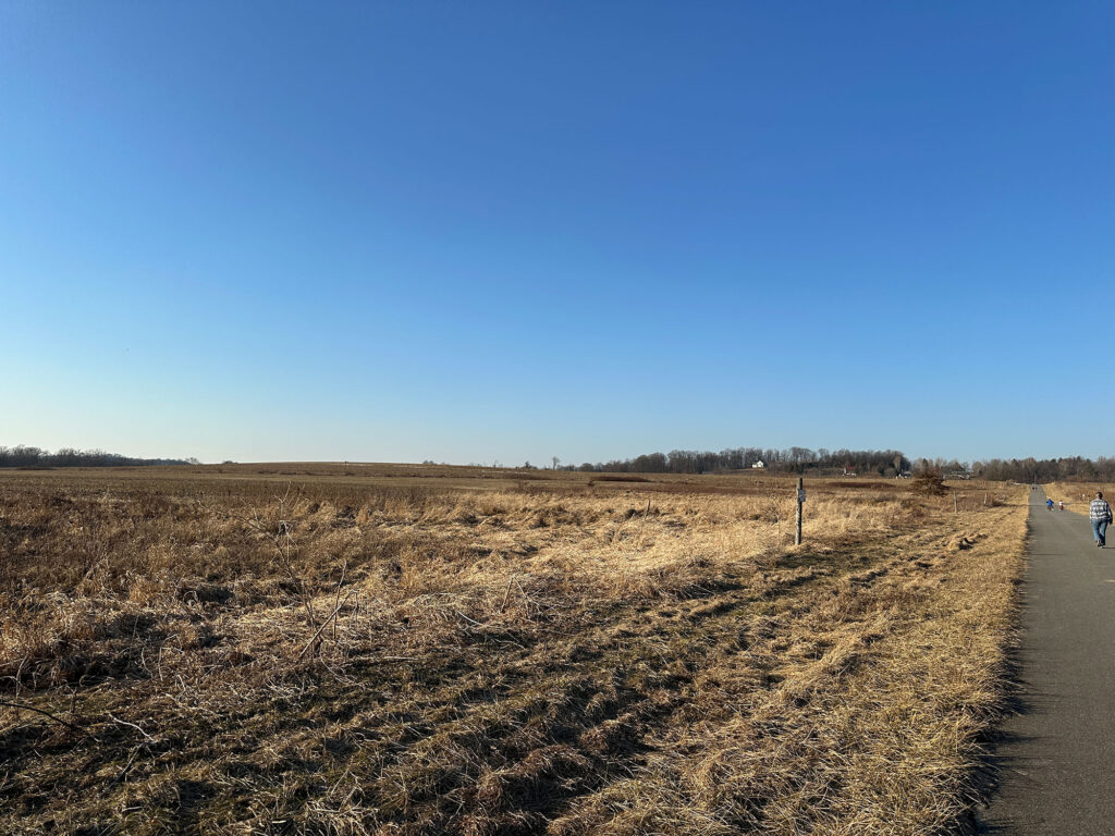 large meadow on the left with a walking path visible on the right side