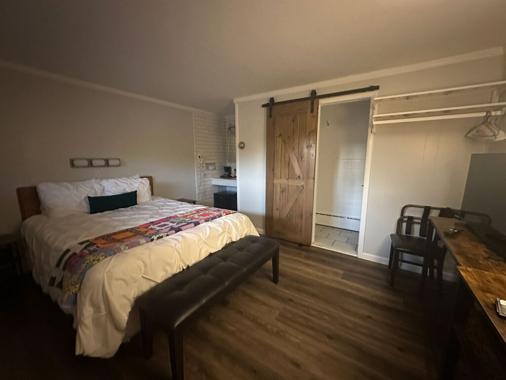 small queen bed hotel room with a sliding barn door along the far wall