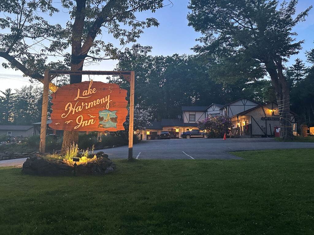 wood sign painted red with the words "Lake Harmony Inn" in yellow script