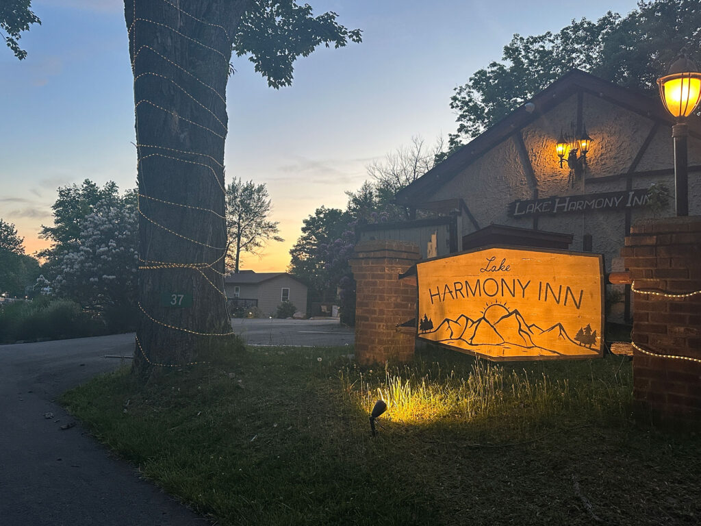 Wooden sign etched with outlines of mountains the words "Lake Harmony Inn"