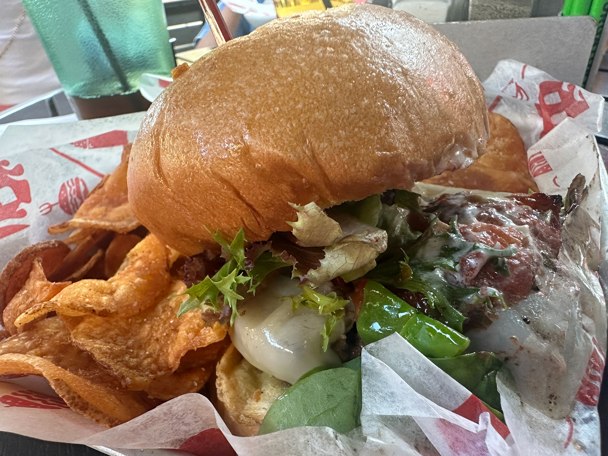 burger with cheese and sauce in a basket with chips